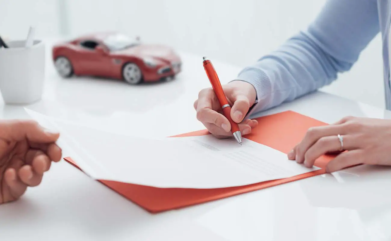 woman signing a car title transfer document