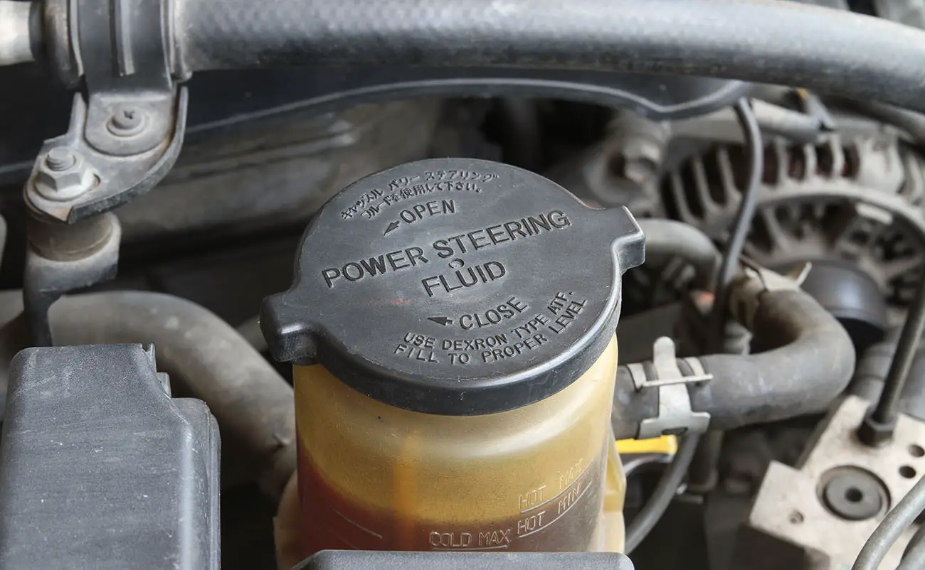 closeup of power steering fluid cap with warning label