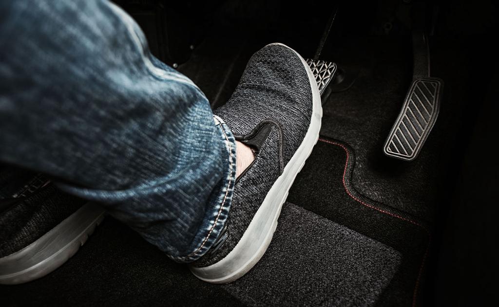 closeup of foot pressing brake pedal of a car