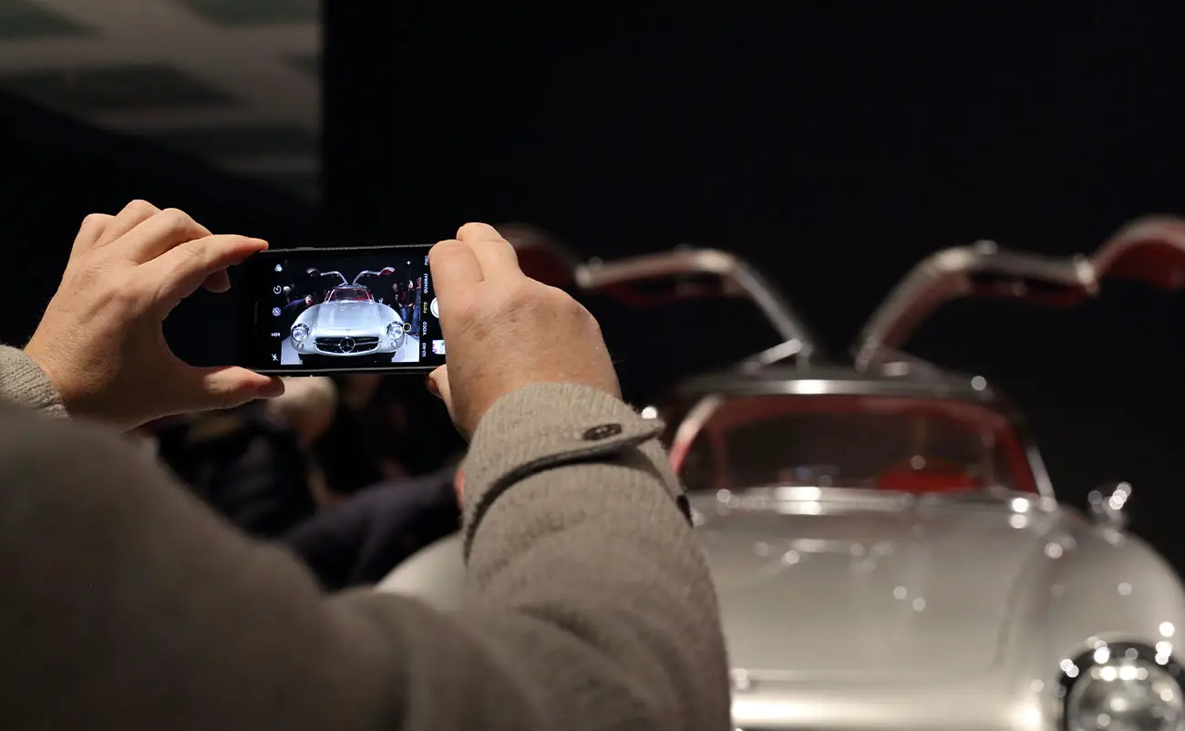 man taking cellphone photo of mercedes 300 sl coupe