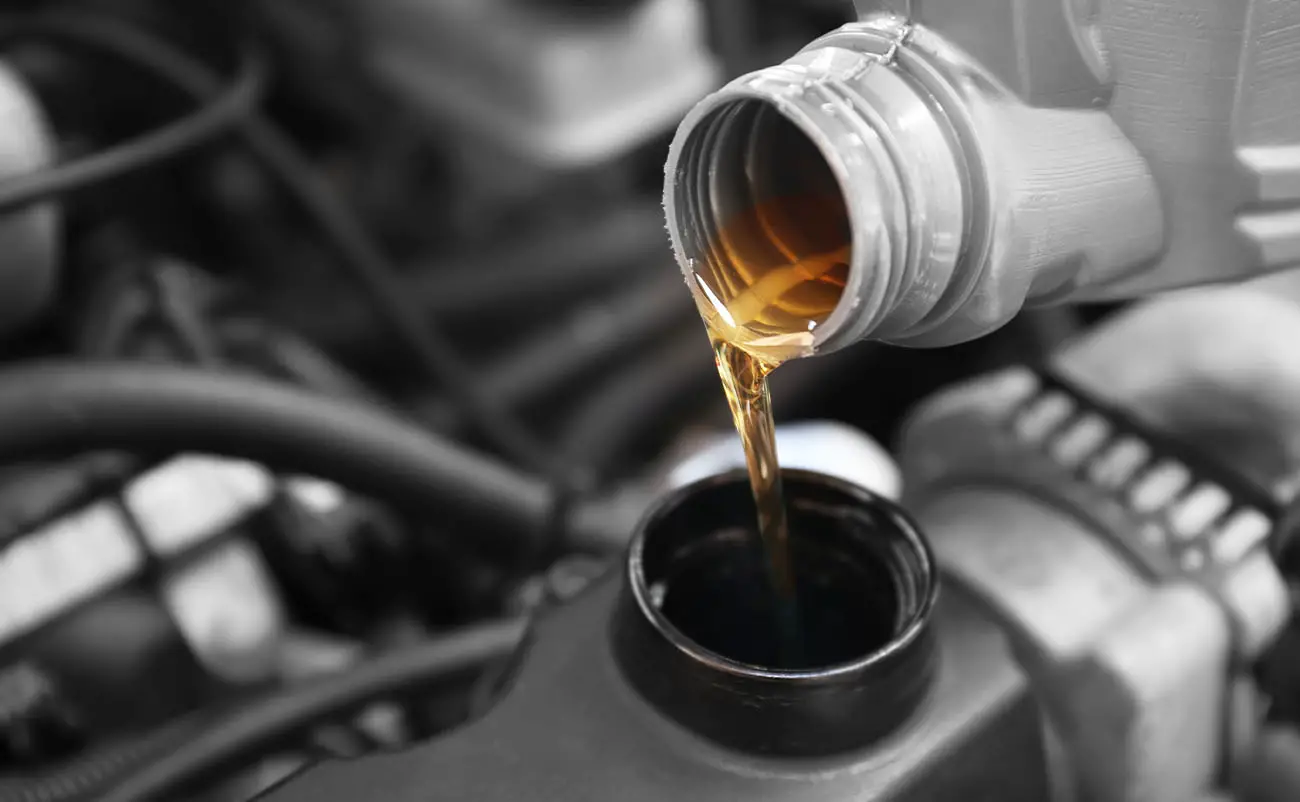 person pouring fresh oil into car engine closeup