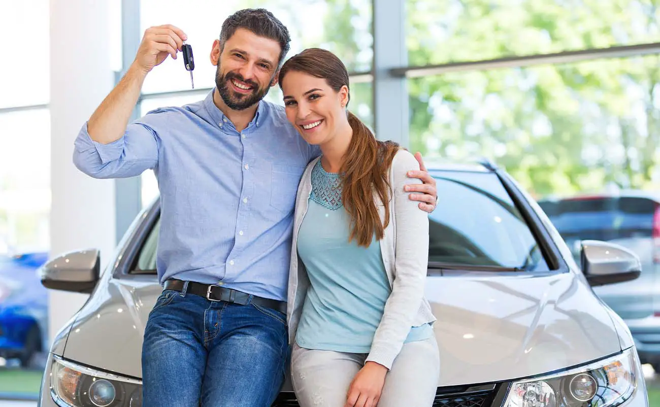 young couple buying a used car from midsize dealership