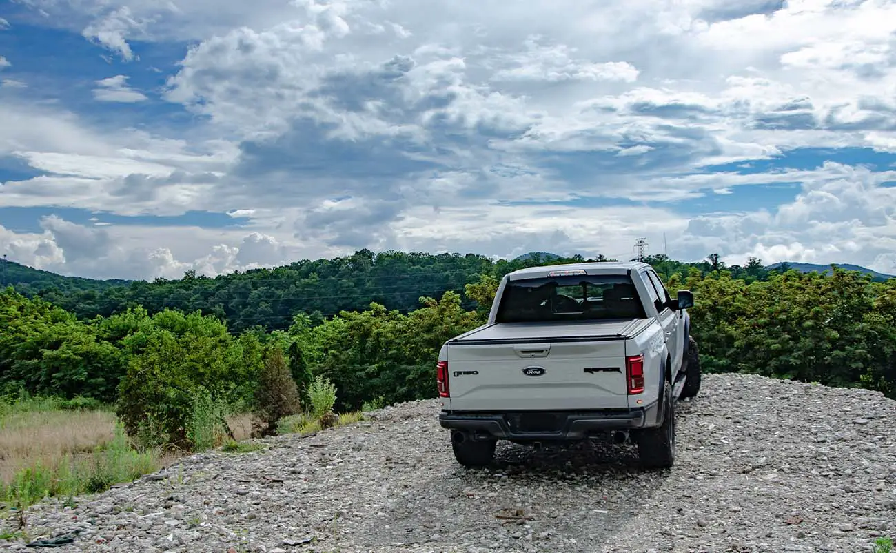 ford f150 raptor parked on gravel facing towards mountains and sky
