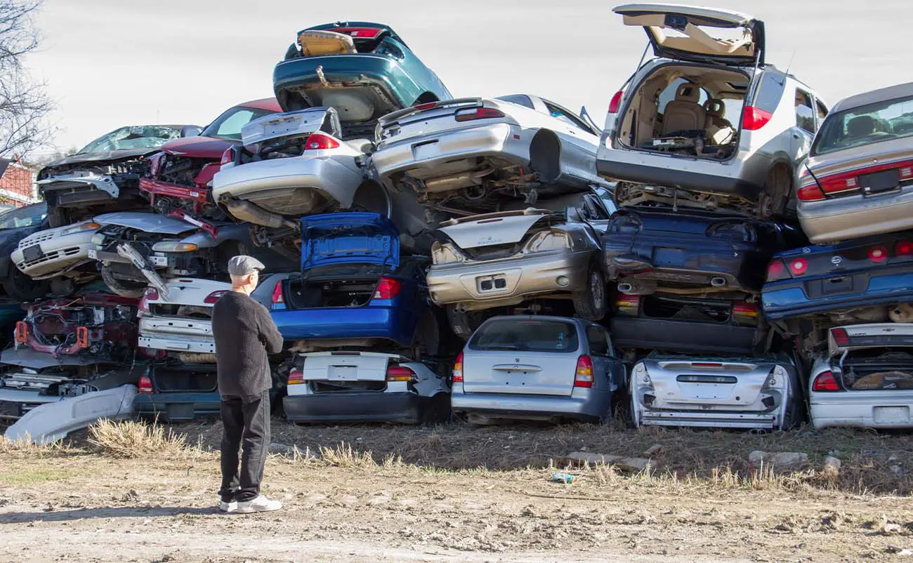 man viewing stacked vehicles in a junkyard